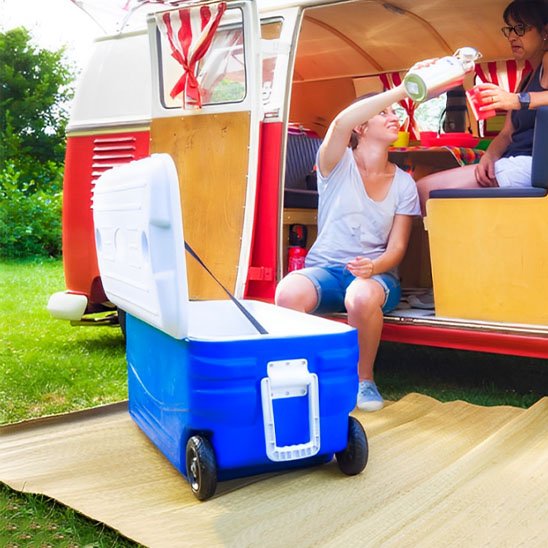 Glacière à roulettes bleue à l'extérieur d'un camping-car, parfaite pour les aventures en plein air.
